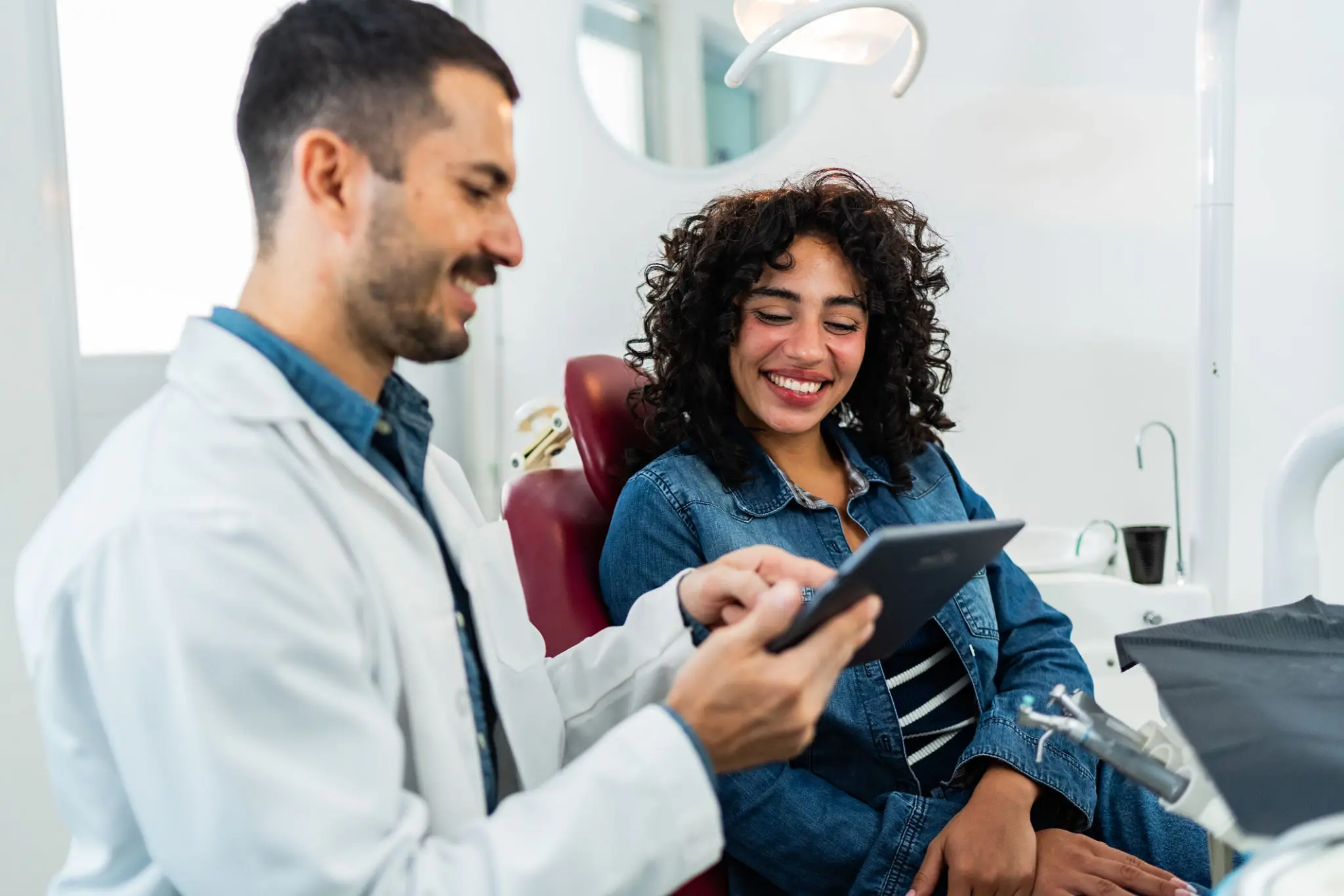 Dentist showing a patient dental x-rays on a tablet.