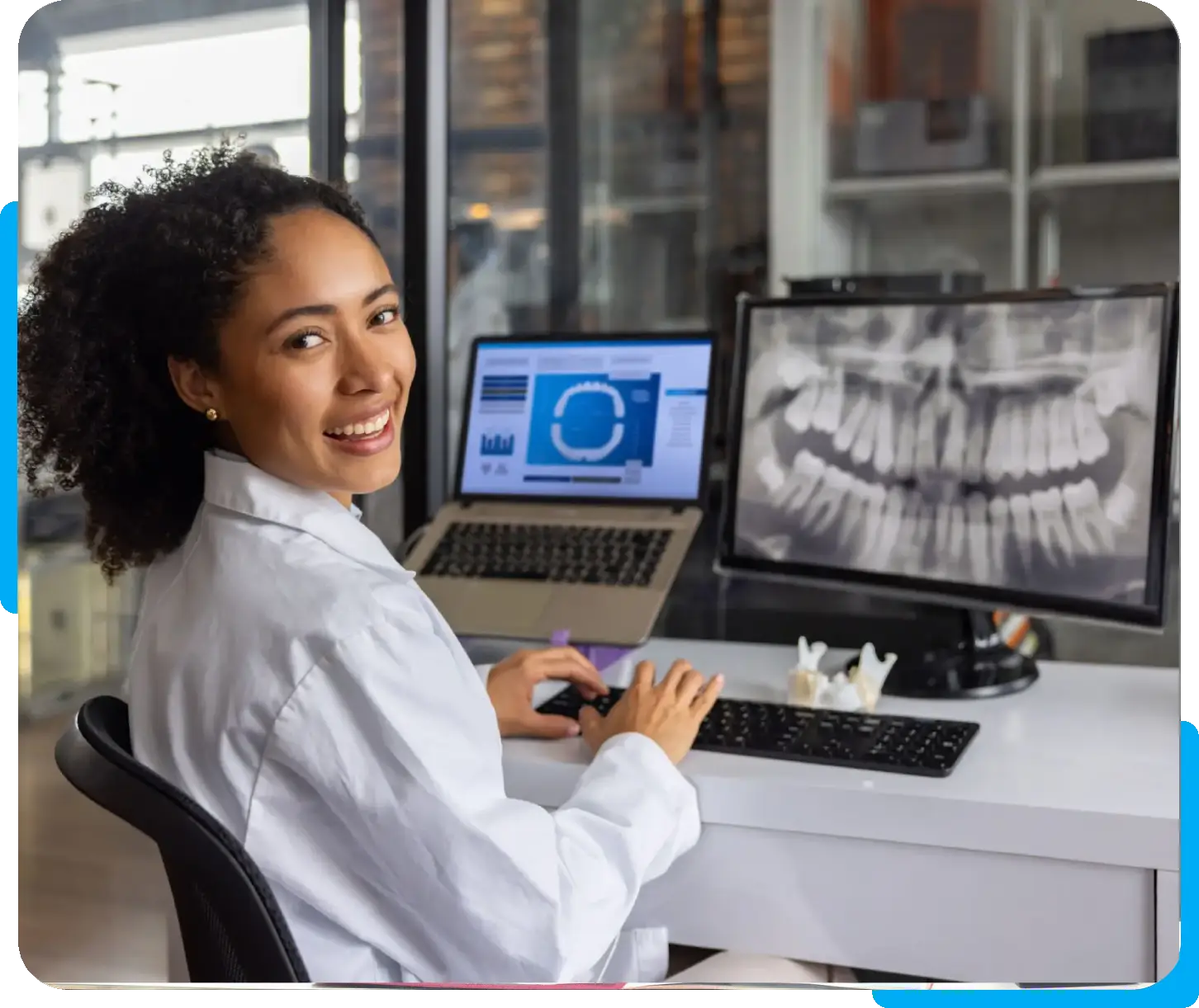 Radiologist analyzing dental X-rays with a laptop and computer screen.
