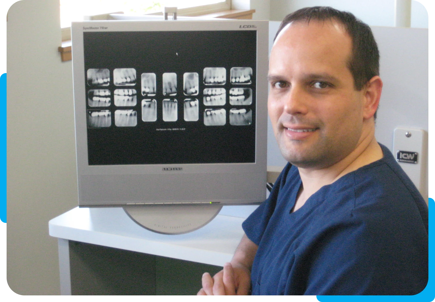 Dentist smiling beside X-ray screen